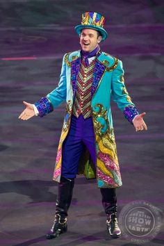 a man in a colorful suit and top hat is standing with his hands out to the side