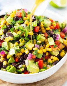 a white bowl filled with black beans, avocado and cilantro dressing