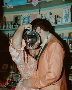 a man and woman standing next to each other in front of a wall with disco balls