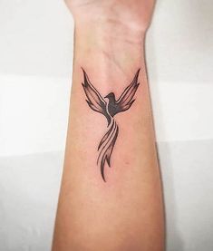 a small tattoo on the wrist of a woman with a bird flying above her arm