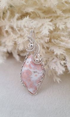 a pink and white stone pendant sitting on top of a pile of fluffy white fur