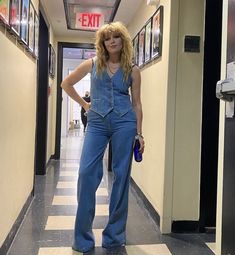 a woman in overalls is standing on the hallway