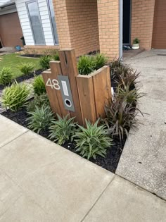 a house number sign in front of some plants