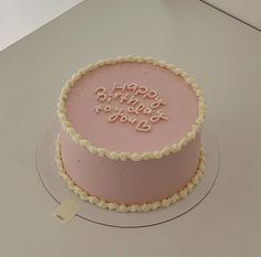 a pink birthday cake sitting on top of a table