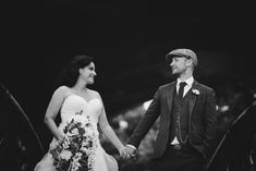 a bride and groom holding hands while walking down the stairs at their wedding ceremony in black and white