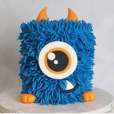 a blue monster cake with orange horns and eyes