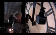 an older man holding onto the back of a large clock