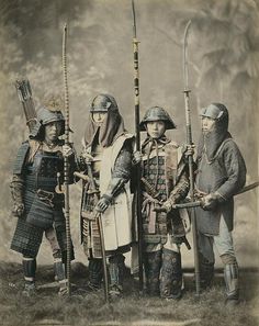 an old photo of four people dressed in medieval clothing and holding spears, standing next to each other