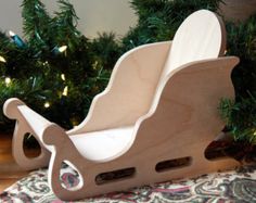 a wooden toy sleigh sitting in front of a christmas tree