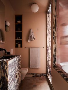 a bathroom with pink walls and marble counter tops