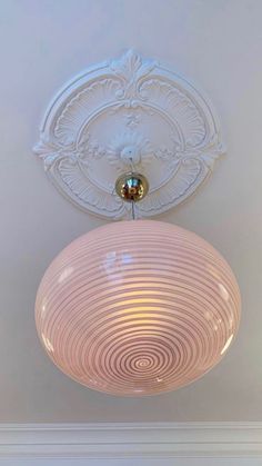 a light fixture hanging from the ceiling in a room with white walls and trimmings