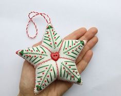 a hand holding an ornament shaped like a star with a red heart on it