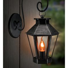 an outdoor light hanging from the side of a door with a candle lit inside it