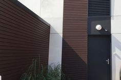 two brown doors are next to each other on the side of a white building with black shutters