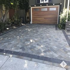 a house with a driveway made out of pavers and wood garage door on the side