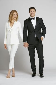 a man in a tuxedo standing next to a woman in a white suit