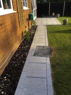 a walkway in front of a brick building with grass and flowers on the ground next to it