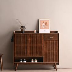 a wooden cabinet sitting next to a table with shoes on it and a framed photograph