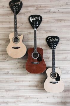 three guitars are hanging on the wall