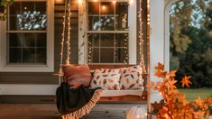 a porch swing with pillows and lights on it