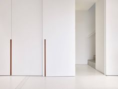 an empty room with white walls and flooring is shown in this image, there are three doors on each side of the wall