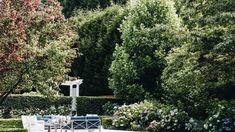 an outdoor dining table and chairs in the middle of a garden with trees around it