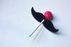 a lollipop with a fake mustache on it's tip is sitting on a white surface