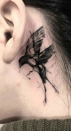 a woman's behind the ear has a black bird tattoo on her left side