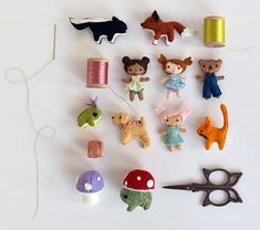 several different types of felt toys are arranged on a table next to scissors and thread