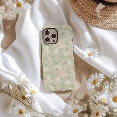 an iphone case sitting on top of a bed of daisies