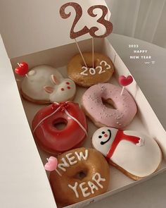 a box filled with donuts covered in frosting next to a happy new year sign