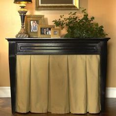 a black and gold console table with pictures on the top, plants in vases next to it