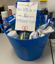 a blue bucket filled with personal care items and a sign that says we will be so shy without you