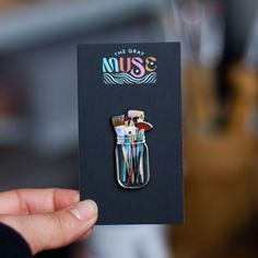 a person holding up a pin with some brushes in it's pocket and the words muss on it