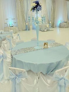 a blue and white wedding set up with flowers in vases on the center table