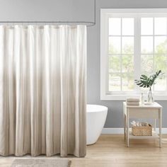 a white bath tub sitting next to a window in a bathroom under a shower curtain