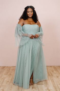 a woman in a dress standing on a wooden floor with her arms around her waist