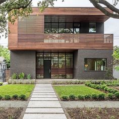 a modern house with large windows and wooden sidings on the front, surrounded by green grass