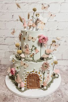 a three tiered cake decorated with flowers and fairy decorations on top of a table