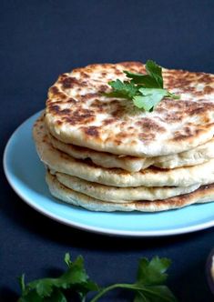 a stack of flatbreads sitting on top of a blue plate with parsley