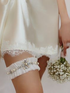 a close up of a person wearing white garters and holding a flower bouquet