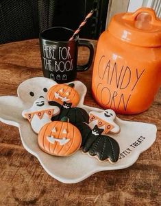 some cookies are on a plate and two mugs sit next to it with halloween decorations