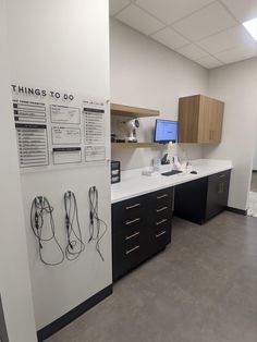 an office cubicle with two computer monitors on the wall and several cords attached to the cabinets