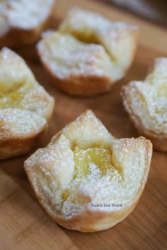 small pastries with powdered sugar on them sitting on a cutting board, ready to be eaten