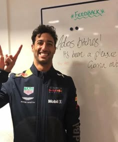 a man standing in front of a whiteboard giving the peace sign