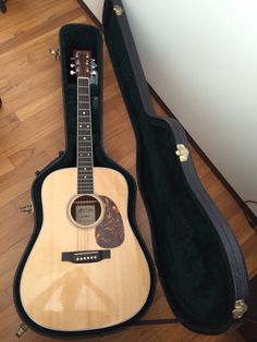 an acoustic guitar is laying on the floor next to its case and carrying it's strap