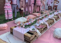 a group of people standing around a table covered in pink cloths and place settings