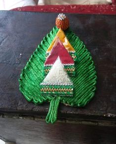 a small christmas tree made out of green yarn on a wooden table with red and white decorations