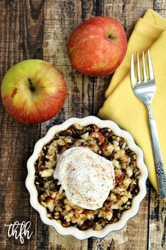 an apple pie with whipped cream on top next to two apples and a yellow napkin