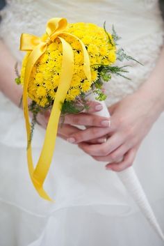 a bride holding a yellow bouquet in her hands